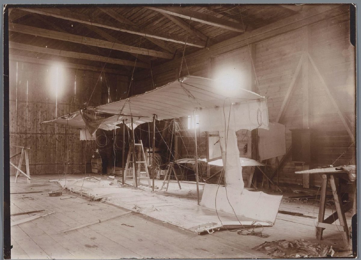 An early aeroplane under construction in a wooden hangar, around 1910